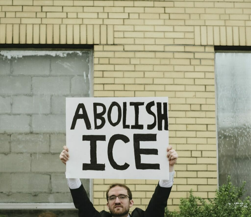 Sujeto sosteniendo una pancarta que dice "Abolish ICE".