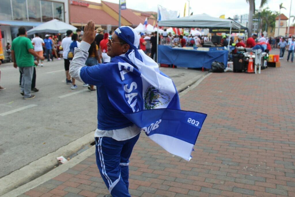 La nota trata sobre la renovación del TPS El Salvador. La imagen muestra a una persona con la bandera de ese país.