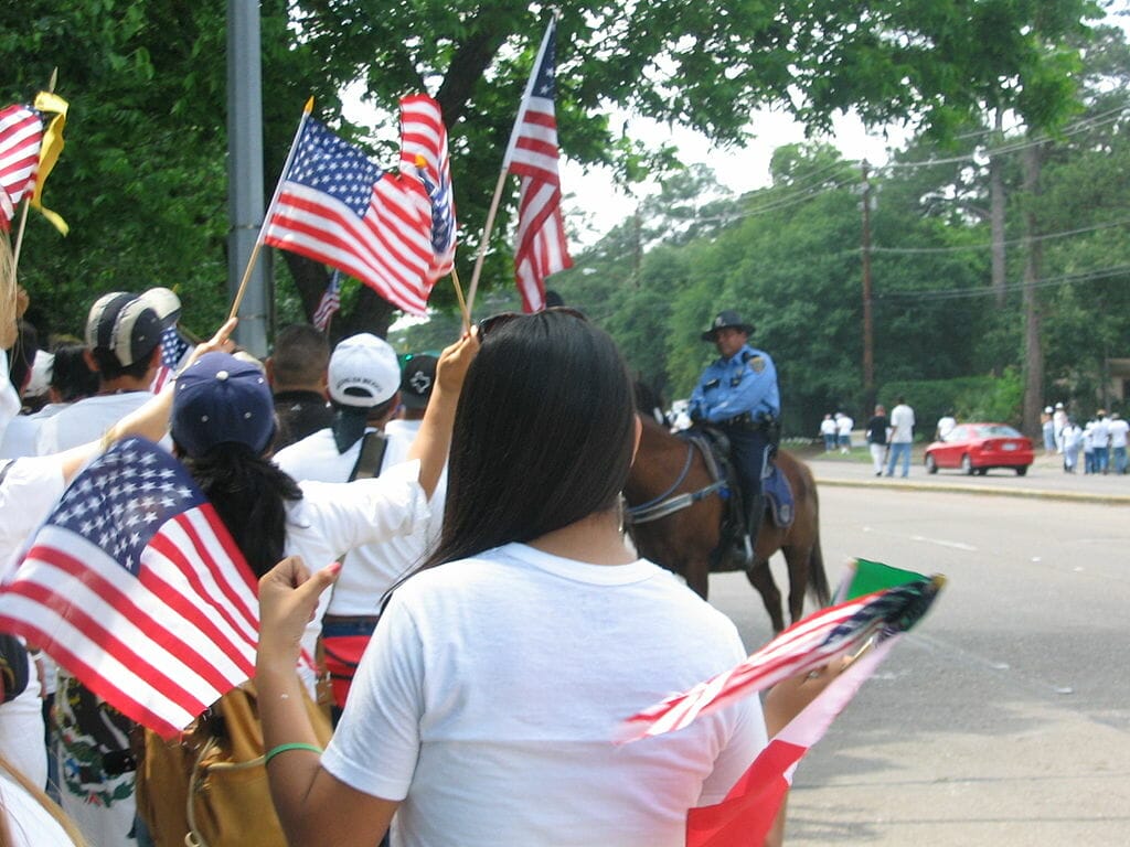 Este artículo habla sobre qué pasa con DACA ahora. La foto muestra un grupo de manifestantes migrantes con banderas de Estados Unidos.