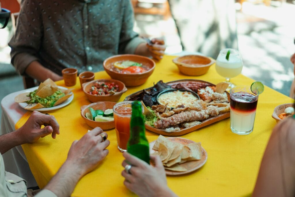 Este artículo habla sobre platos latinos populares en Estados Unidos. La foto muestra una mesa con comida latina donde hay varios comensales.