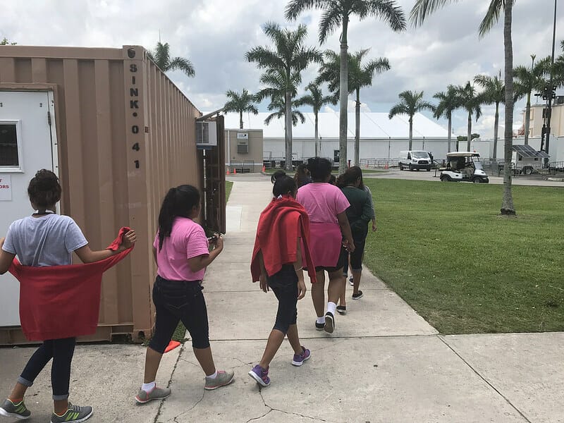 Este artículo habla sobre los migrantes menores no acompañados. La imagen muestra un grupo de chicas migrantes menores en un refugio en Florida.