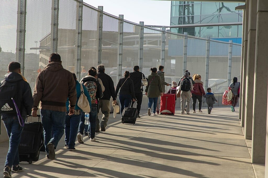 Este artículo habla sobre la nueva política de asilo en la frontera. La imagen muestra a un grupo de solicitantes haciendo fila para ser procesados en un punto de ingreso.