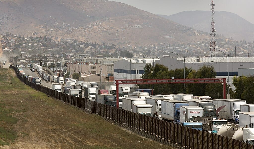 Este artículo habla sobre el bloqueo en la frontera. La imagen muestra una fila de camiones esperando para ingresar a los Estados Unidos por vía terrestre.