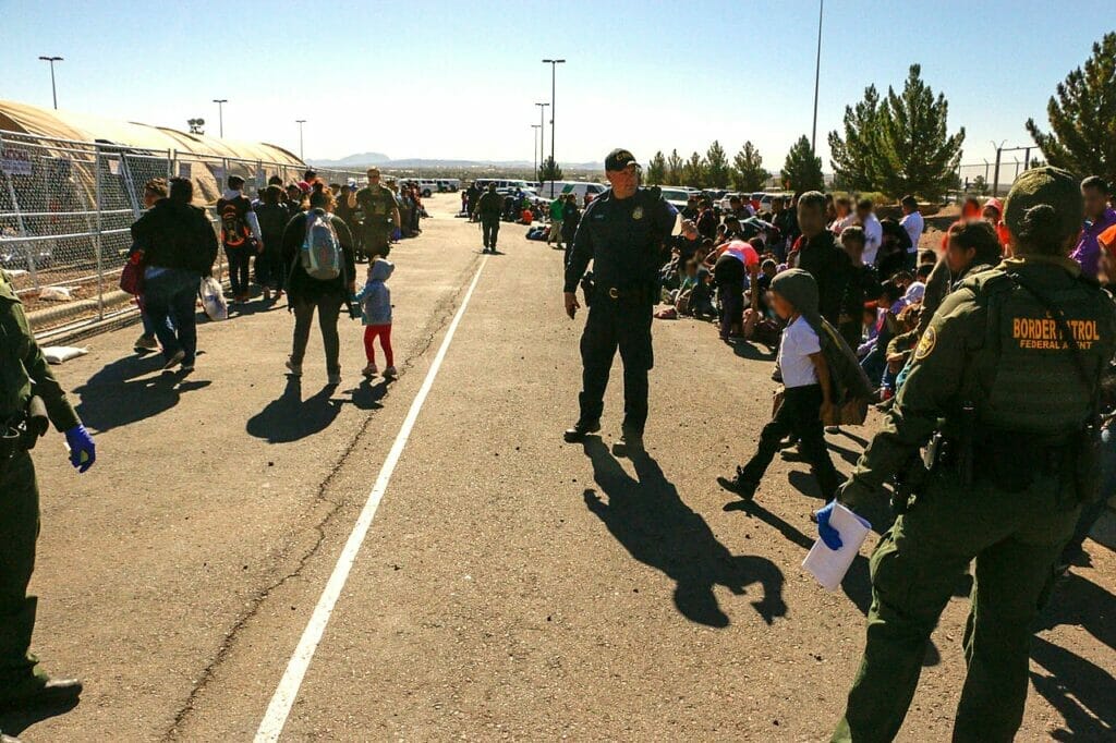 Este artículo habla sobre la posible declaración de emergencia en la frontera en El Paso, Texas. La imagen muestra una caravana detenida por oficiales de la ley.