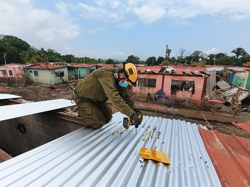 Este artículo habla sobre el pedido de TPS para Centroamérica. La imagen muestra un soldado arreglando un techo en El Salvador.