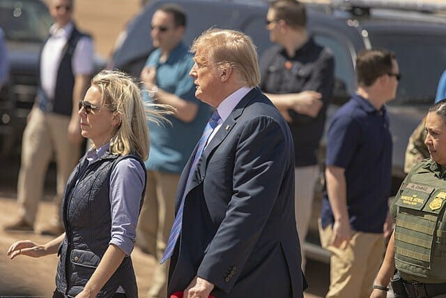 Este artículo habla sobre la separación de familias migrantes. La imagen muestra al ex presidente Donald Trump acompañado por Kirstjen Nielsen, secretaria de DHS durante su mandato, mientras ambos visitan la frontera sur.