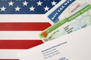 Tarjeta verde, tarjeta de seguro social y documento de migraciones sobre bandera de Estados Unidos.