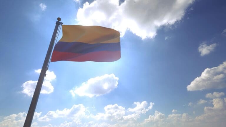 Bandera de Colombia sobre un maste y el cielo azul con nubes blancas de fondo. Este artículo habla sobre el pedido de Colombia a Estados Unidos para brindar "salida forzosa diferida" a algunos colombianos viviendo en el país.