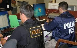 Oficiales de ICE trabajando en computadoras.