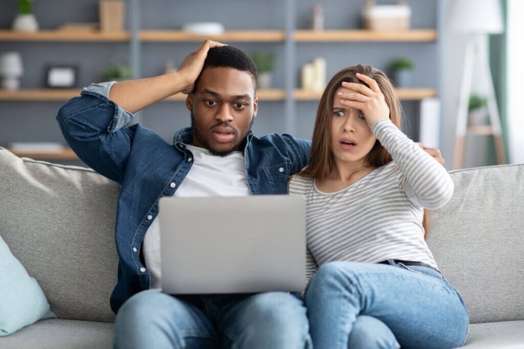 Pareja sorprendida mirando a computadora portátil