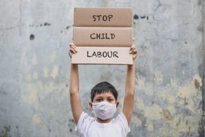 Niño sosteniendo un cartel que dice "Frenen el trabajo infantil"