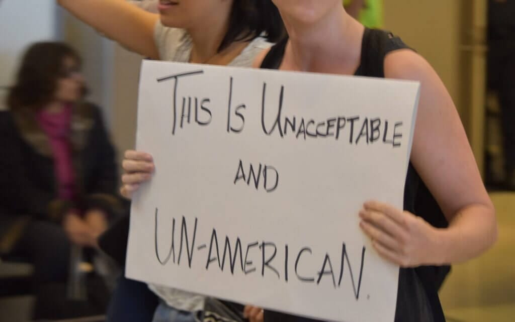 Mujer protestando sosteniendo un cartel que dice "Esto es inaceptable y no americano"