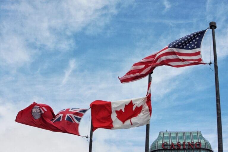 Tres banderas flameando en la frontera de Estados Unidos y Canada