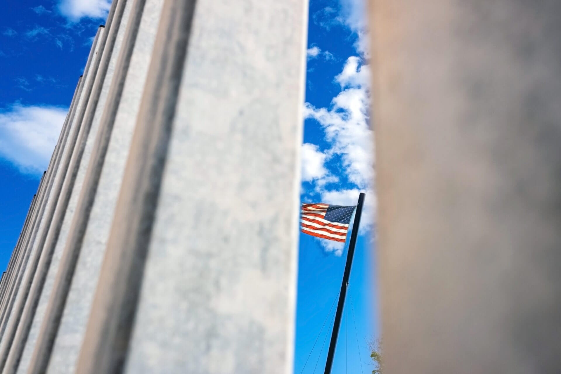 Bandera de los Estados Unidos vista a través del muro fronterizo, simbolizando los centros de procesamiento USCIS de inmigración.