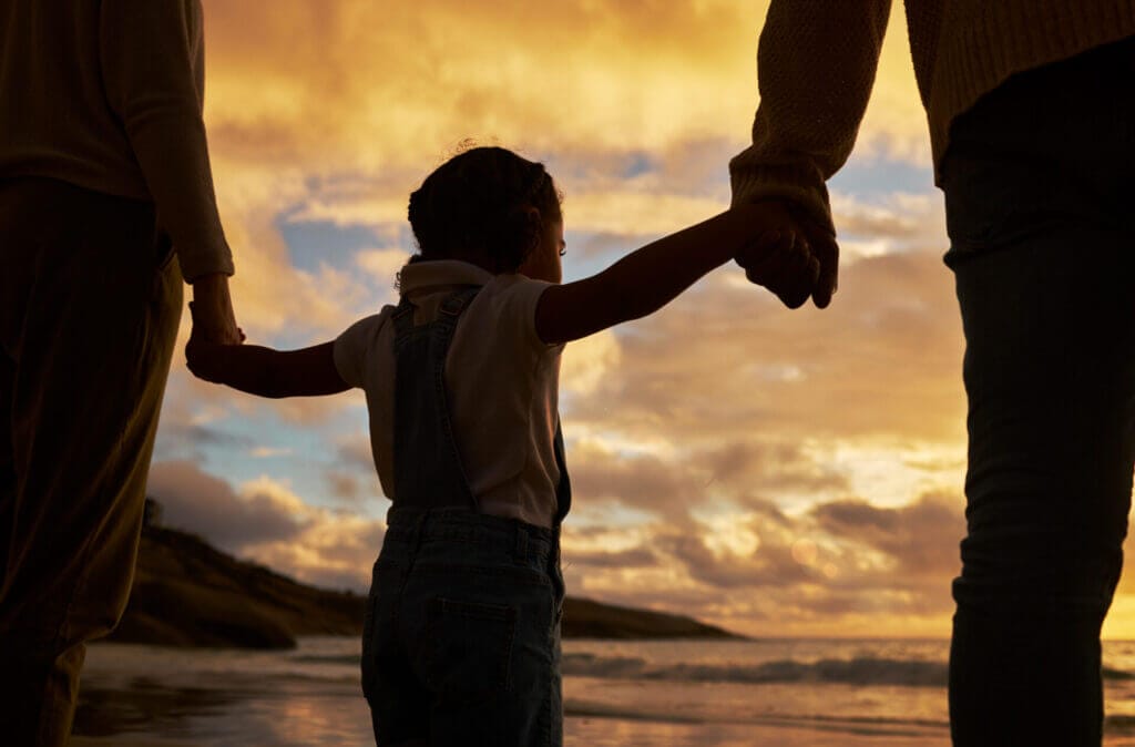 Familia de migrantes mirando el atardecer tomados de la mano, representando la dureza de la separación de familias en la frontera