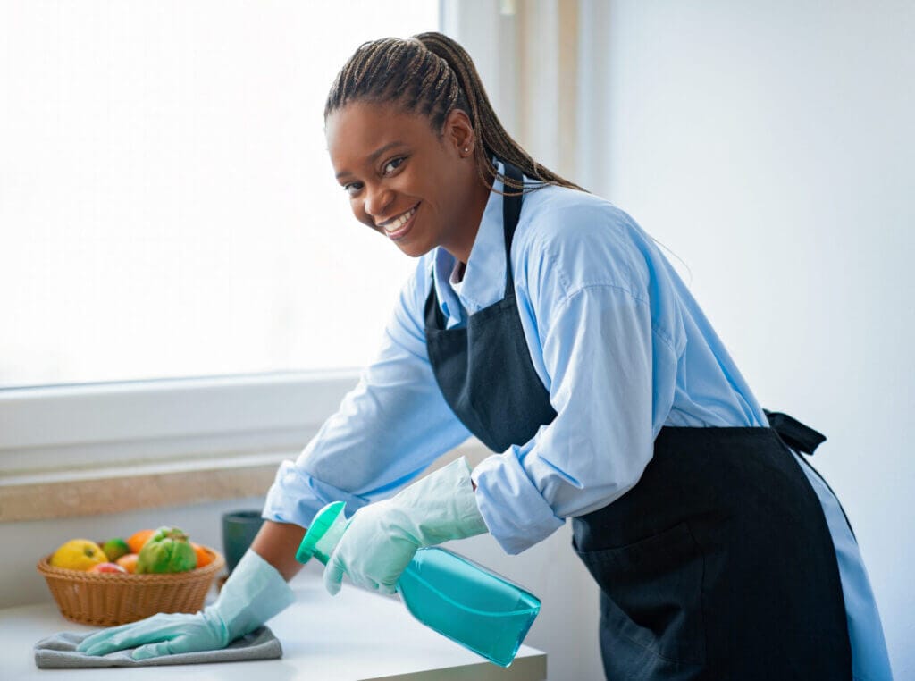 Empleada doméstica limpiando la cocina y sonriendo a la camara luego de obtener su visa b1 empleada domestica