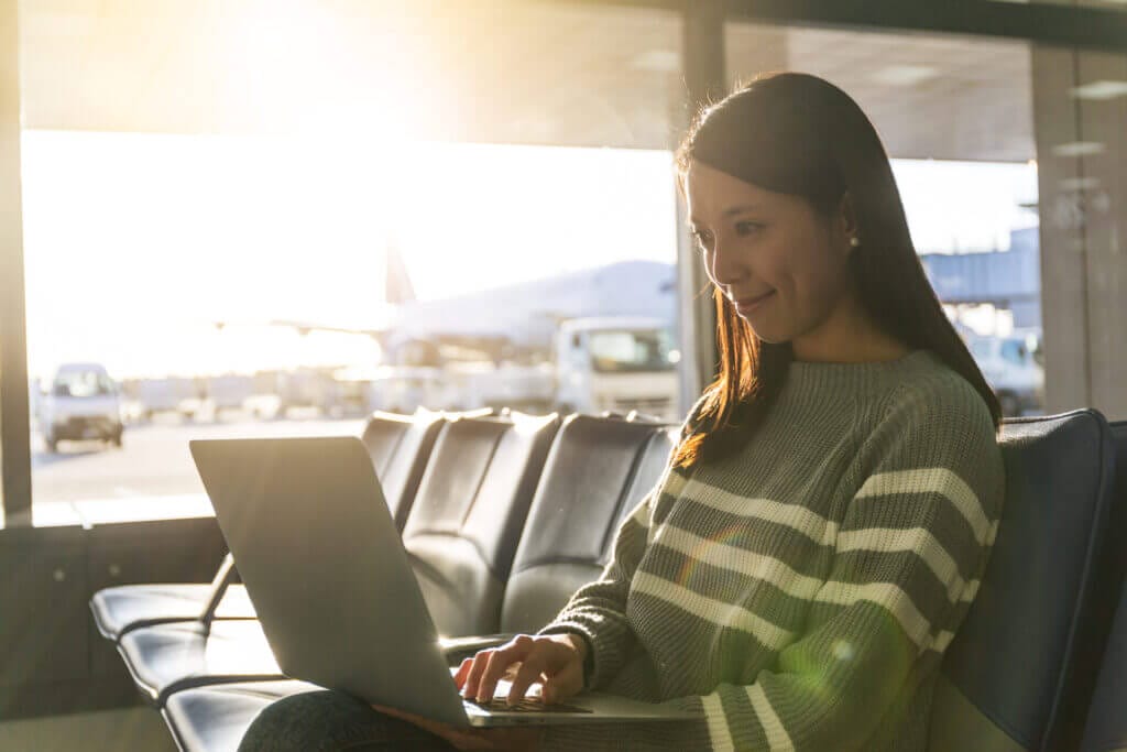 Mujer usando su laptop en el aeropuerto mientras hace una escala en USA
