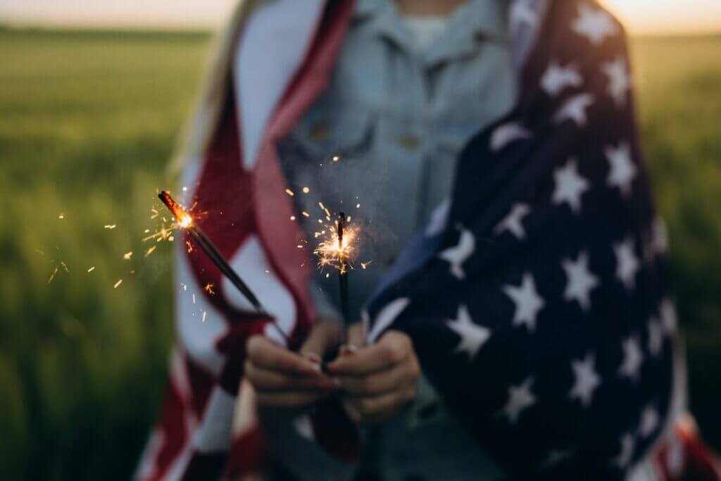 Niña con bandera de Estados Unidos y estrellitas en la mano, celebrando el Dia de la Independencia USA