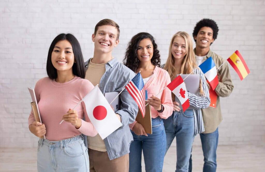 Grupo de jóvenes extranjeros en Estados Unidos posando y riendo con sus respectivas banderas de origen 