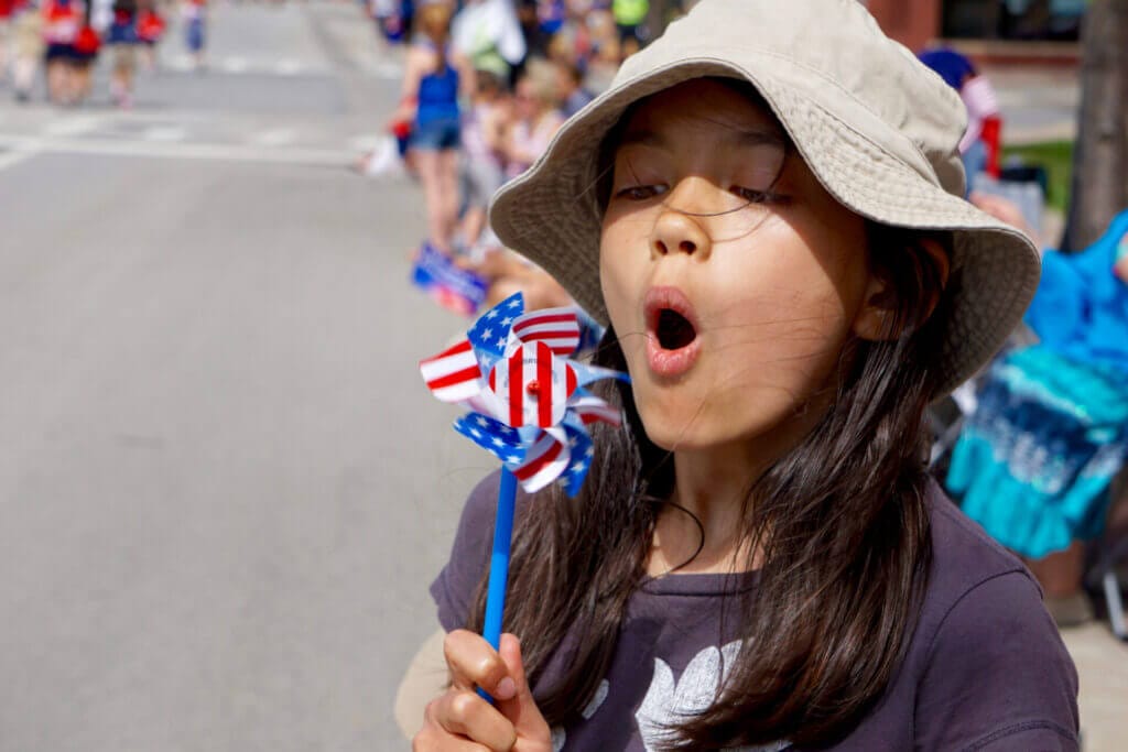 Niña migrante sopla una vela patriótica en desfile por el 4 de julio