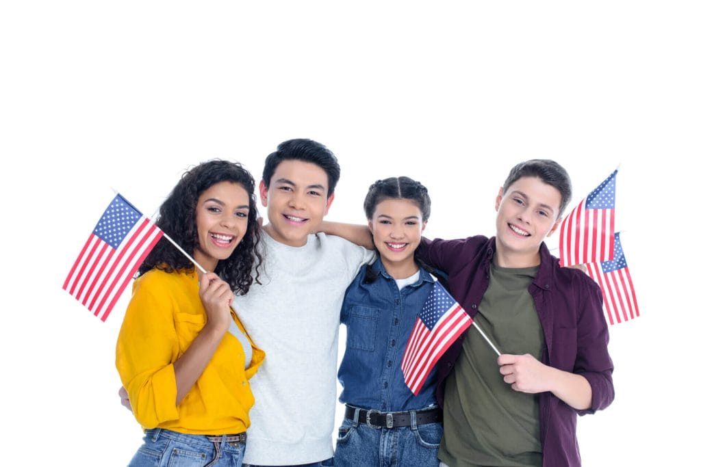 Grupo de estudiantes de intercambio sonriendo con la bandera de USA luego de averiguar cómo puedo cambiar mi estatus de turista a estudiante en USA