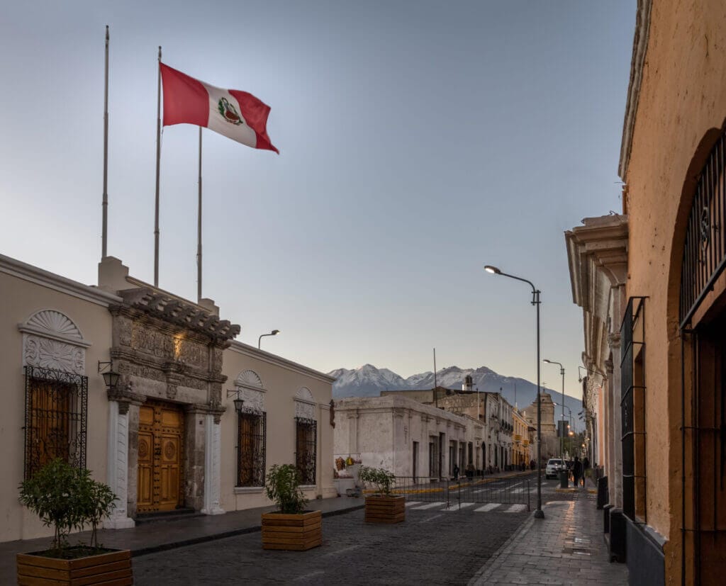 Calles de Arequipa con la bandera de Perú flameando en el cielo