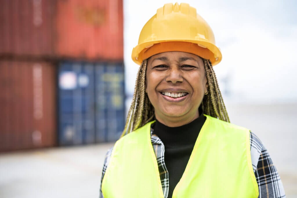 Rostro de una mujer sonriendo a la cámara trabajadora fabril con uniforme y casco