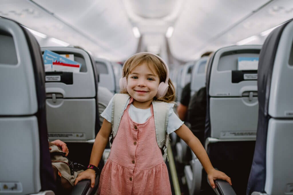 Niña pequeña sonriendo entre los asientos de un avión