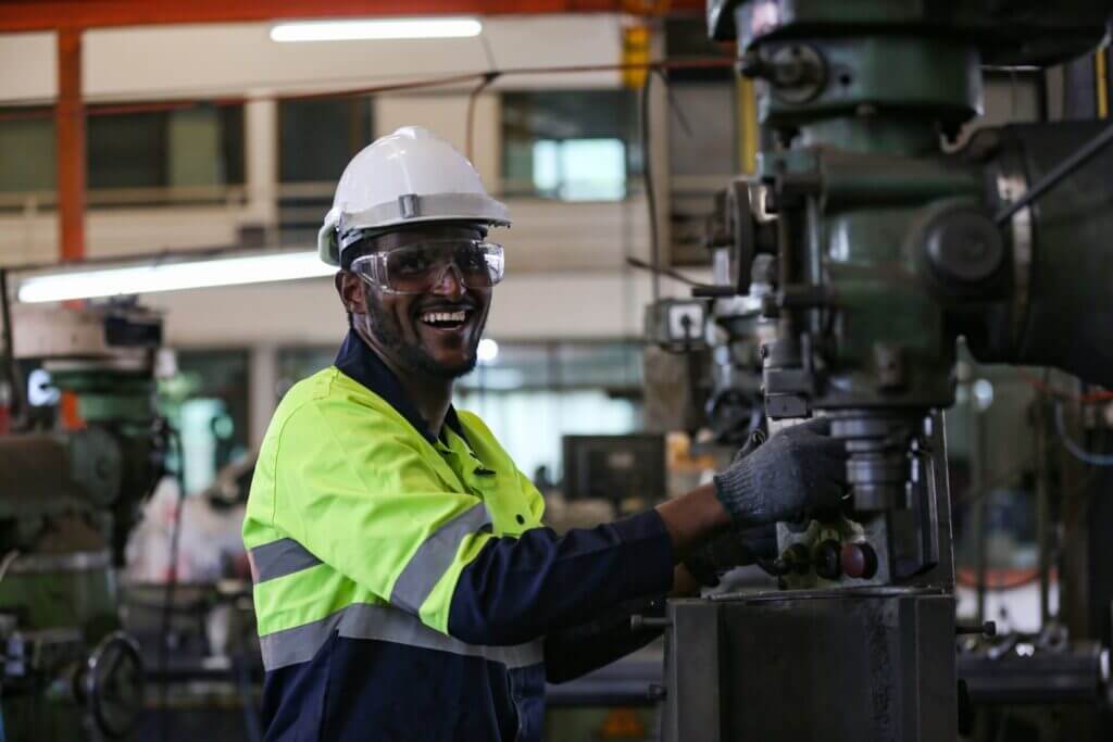 Trabajador en fábrica utilizando máquinas y sonriendo