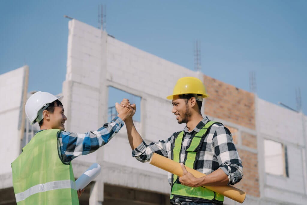 Dos trabajadores de construcción estrechándose la mano y sonriendo