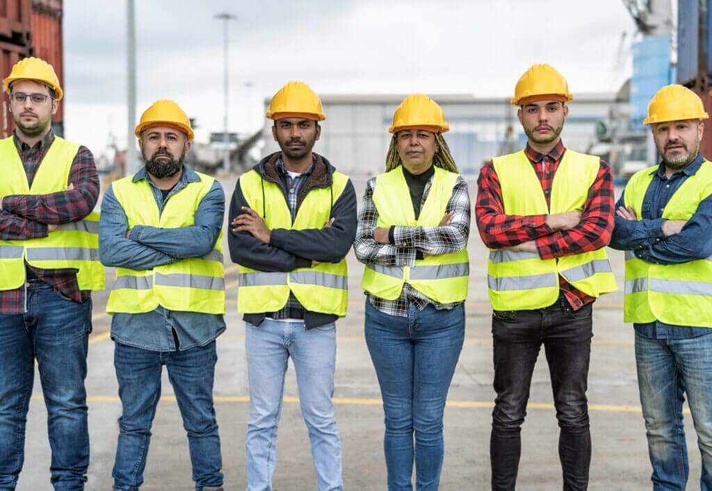 Grupo de diversos migrantes ingenieros posando uniformados en su espacio de trabajo