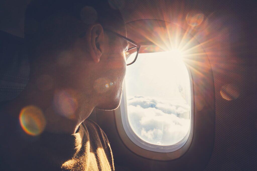 Hombre mirando el atardecer por la ventana de un avión