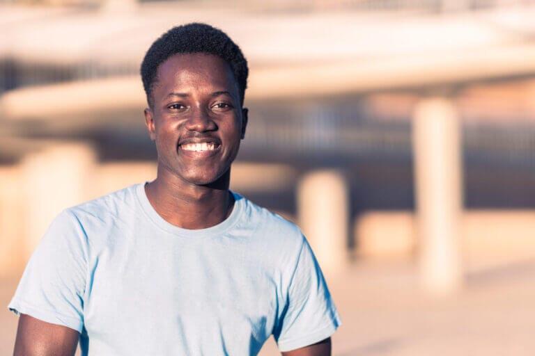 Joven migrante sonriendo a la cámara tras obtener un Estatus Juvenil para Inmigrantes en EEUU