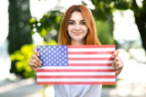 Mujer sosteniendo una bandera de USA celebrando su nuevo estado migratorio legal