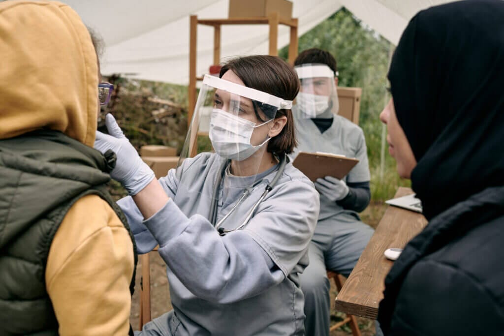 Mujer realizando un examen medico a un grupo de refugiados en usa