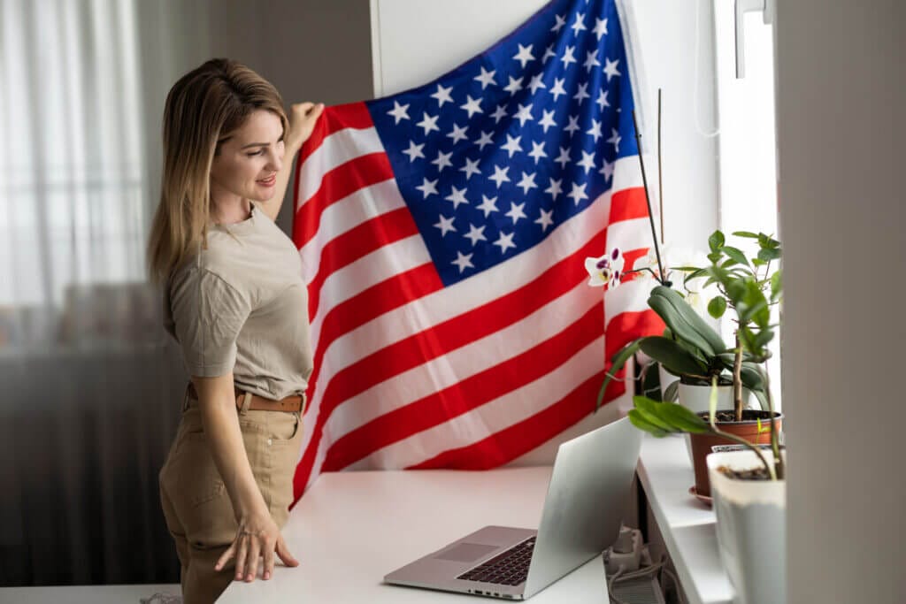 Fotografía de una mujer frente a su laptop colgando la bandera de EEUU
