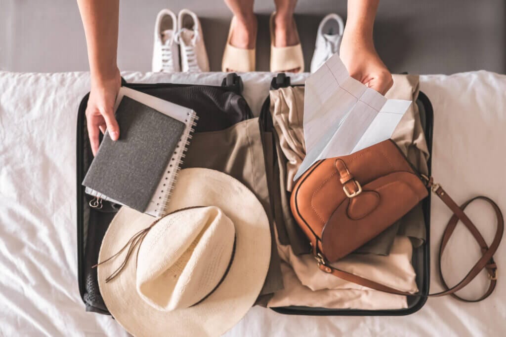 Imagen conceptual de una maleta de viaje con documentos, gorro y cartera