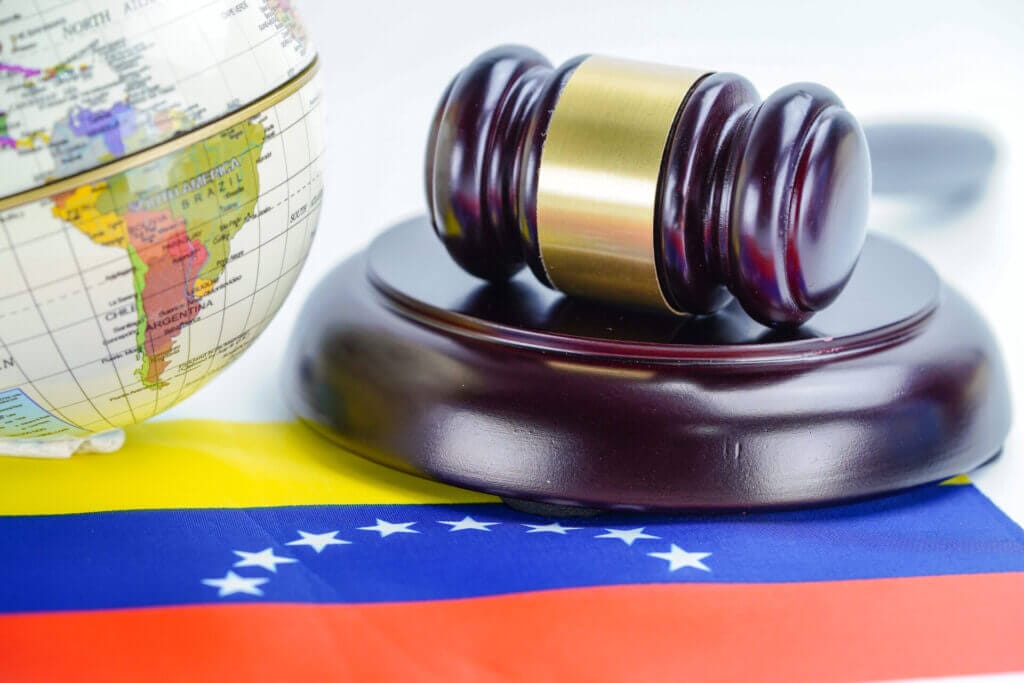 Bandera de Venezuela con un martillo de justicia y un globo terráqueo encima en representación de la inmigración 