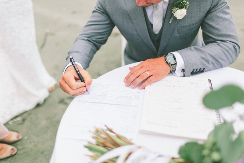 El novio sentado en una mesa firmando los documentos de matrimonio