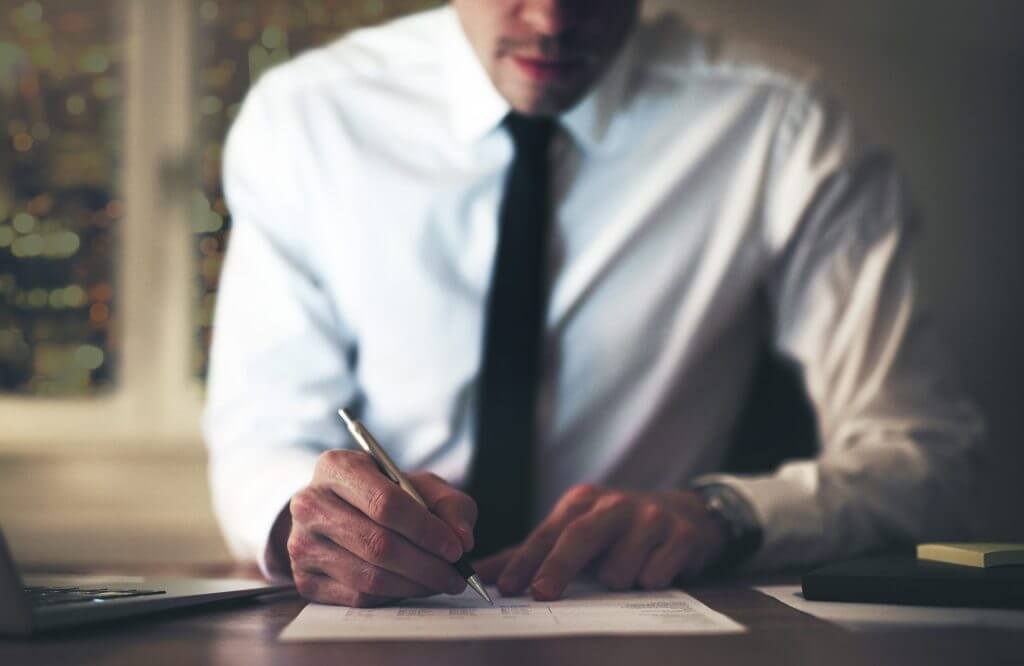 Hombre en traje escribiendo la carta de recomendacion para inmigracion