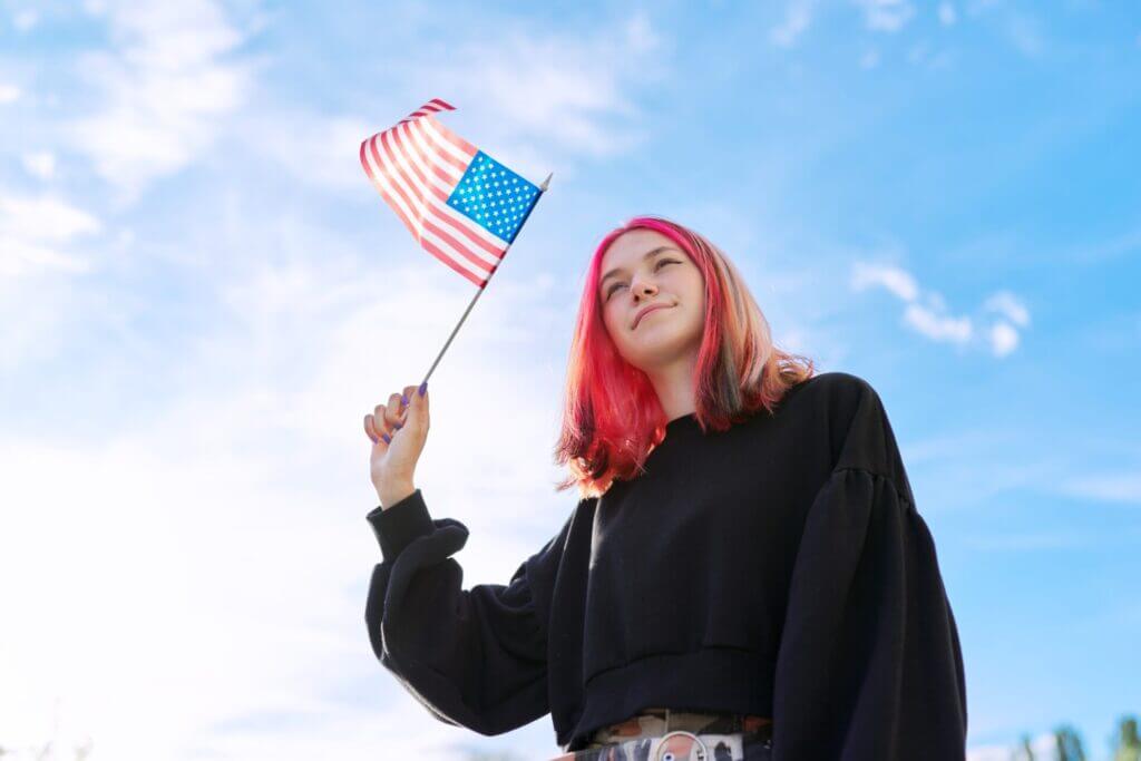 Joven migrante con bandera de USA tras haber ingresado al país