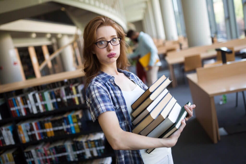 Estudiante joven en la librería con una pila de libros