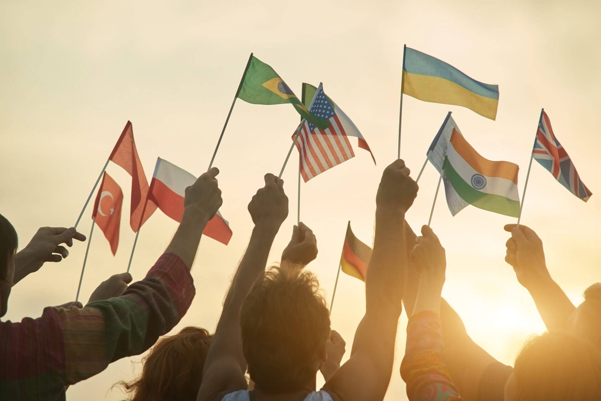 Varias personas con banderas multinacionales levantadas al cielo en señal de las protestas de migrantes
