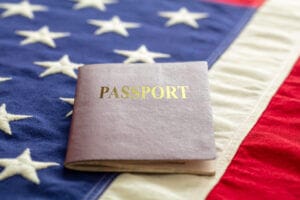 Imagen conceptual de un pasaporte con la bandera de USA de fondo, representando que es ESTA en migración