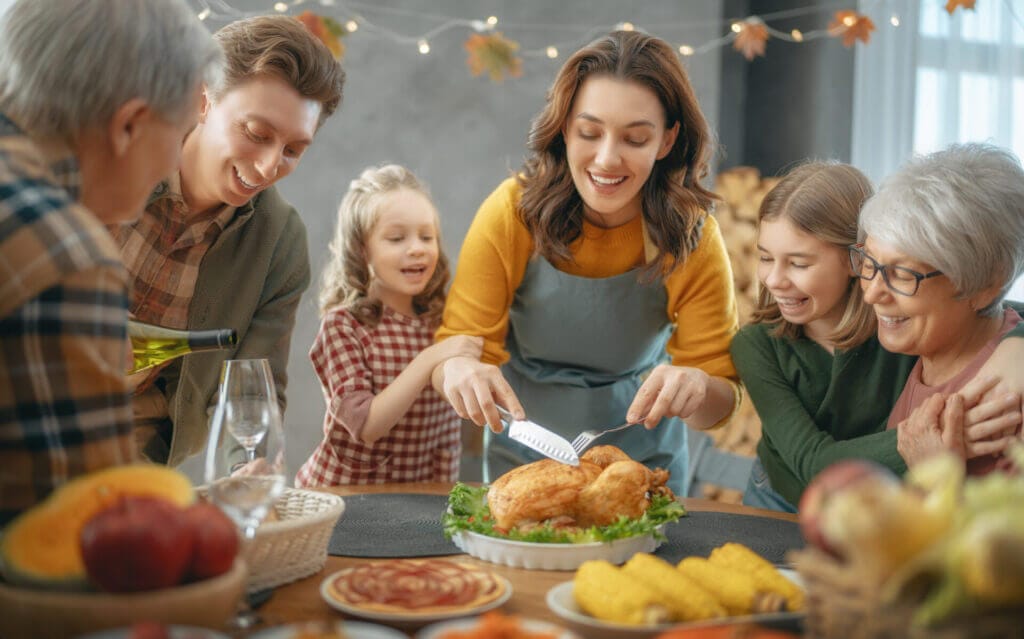 Familia feliz reunida por Acción de Gracias cortando el pavo