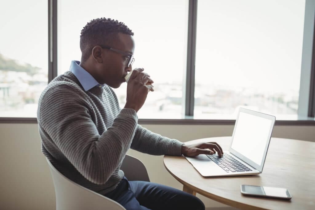 Hombre migrante tomando café mientras aprende cómo verificar estatus de mi caso