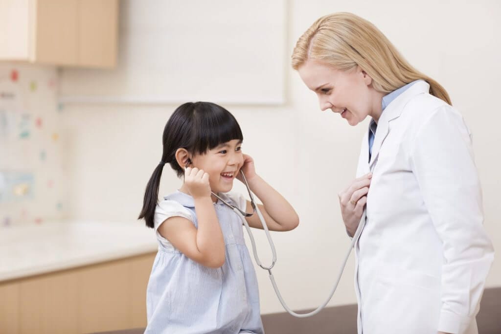 Doctora y niña pequeña sonriendo en una consulta pediátrica