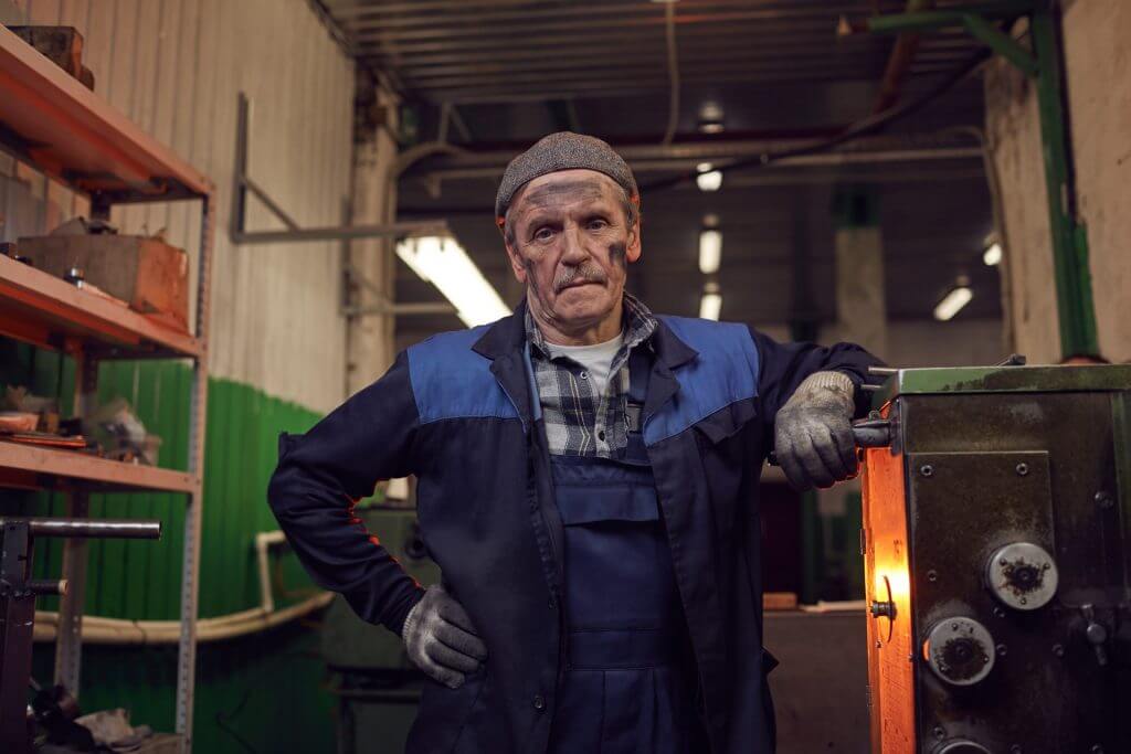 Hombre mayor en una planta de trabajo con la cara llena de carbón