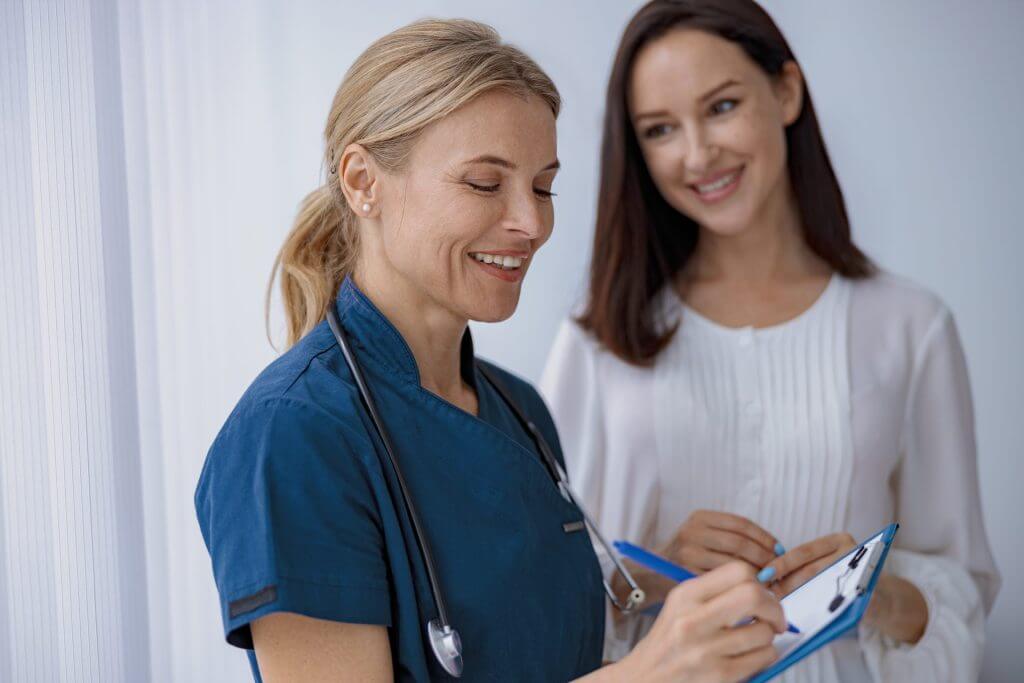 Doctor sonriendo a su paciente mientras le escribe el parte médico