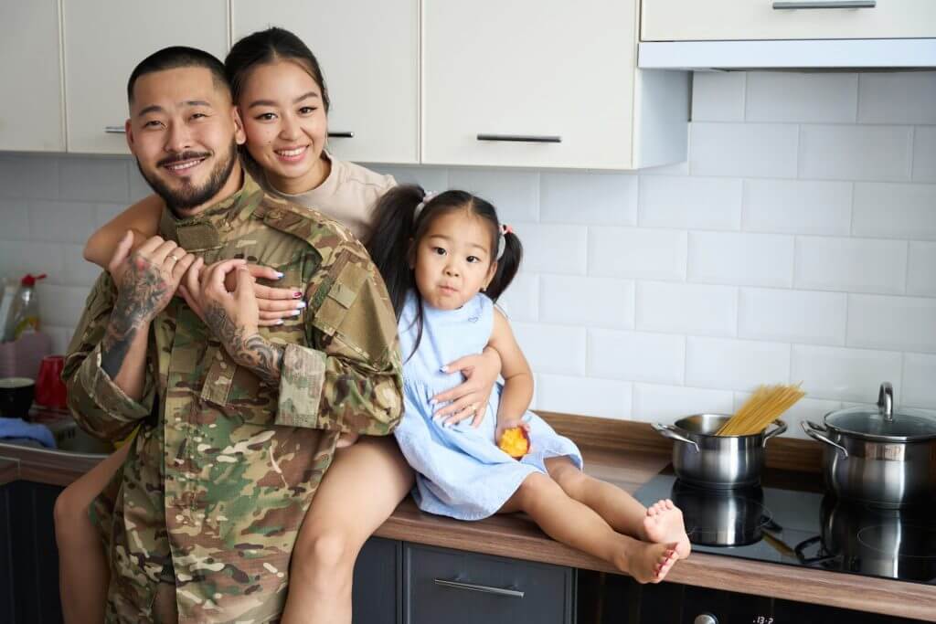 Familia con padre militar abrazándose en la cocina mientras posan para la cámara